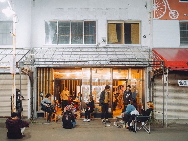 夕方の商店街、店先に集まる人たち
